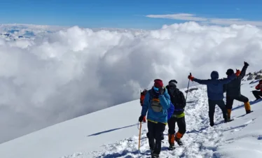 在 哈巴雪山 山頂雪原上，登山者結伴前行，腳踏積雪，遠處雲海翻湧，展現壯闊高山探險景象。