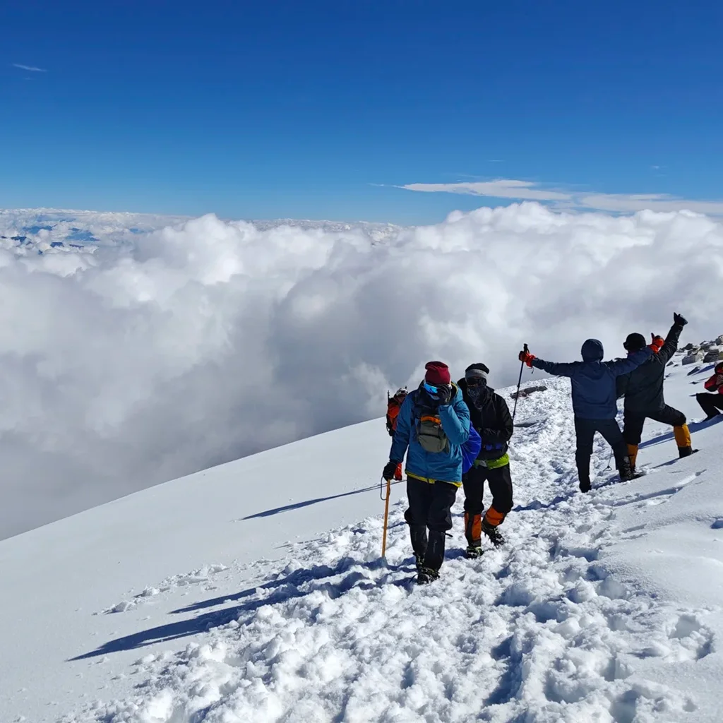 在 哈巴雪山 山頂雪原上，登山者結伴前行，腳踏積雪，遠處雲海翻湧，展現壯闊高山探險景象。