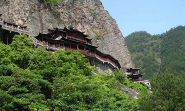 昆明西山懸崖上的古建築群沿著山壁而建，木質樓閣與棧道依山勢蜿蜒延伸，四周被茂密山林與峭壁環繞，展現西山龍門景區險峻壯麗的自然山景與歷史人文建築特色。