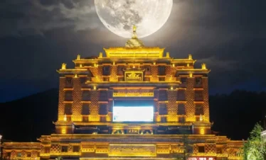 夜幕下的 香巴拉時輪壇城 金碧輝煌，巨大的滿月高懸於建築上方，形成震撼視覺效果。