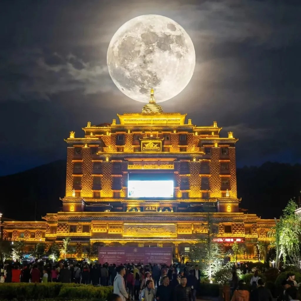 夜幕下的 香巴拉時輪壇城 金碧輝煌，巨大的滿月高懸於建築上方，形成震撼視覺效果。