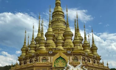 在 勐泐大佛寺，金碧輝煌的佛塔群層層疊起，白象雕塑佇立前方，建築融合南傳佛教風格，氣勢宏偉莊嚴。