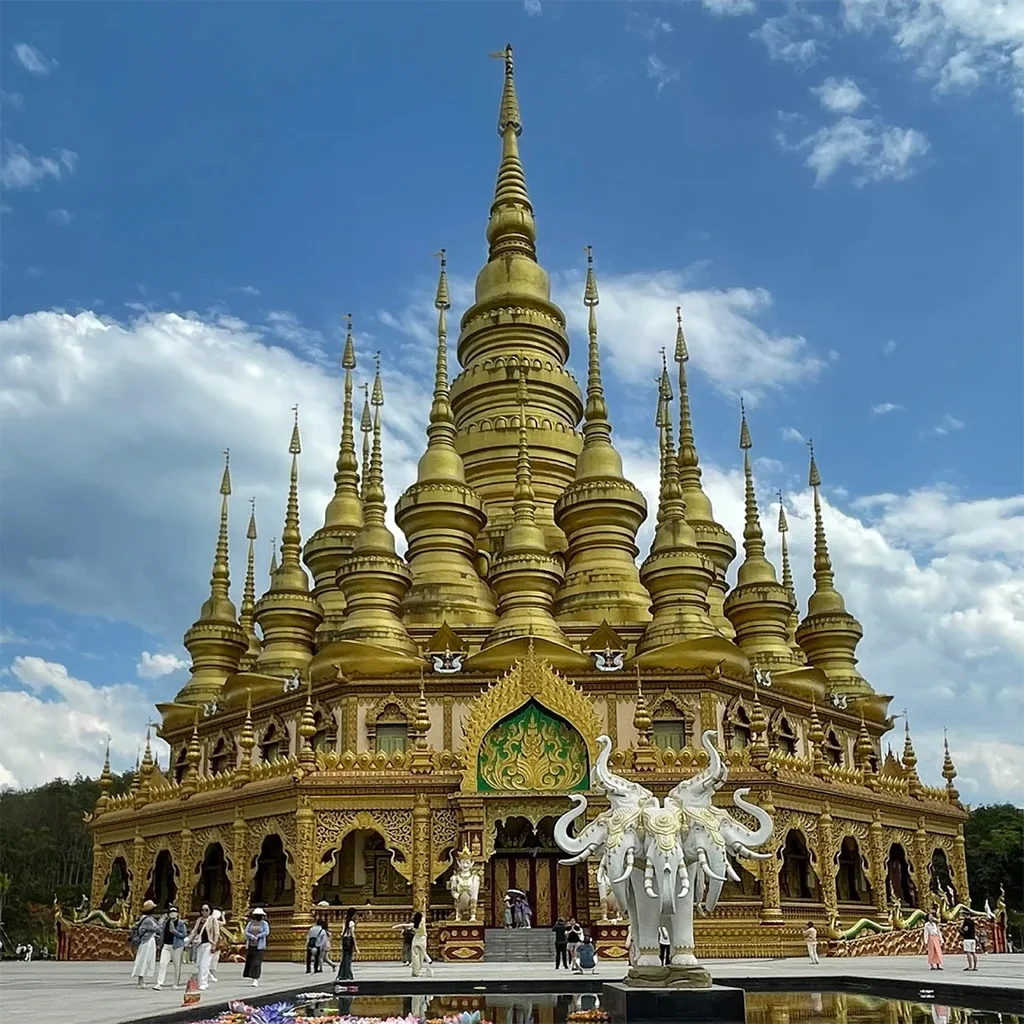 在 勐泐大佛寺，金碧輝煌的佛塔群層層疊起，白象雕塑佇立前方，建築融合南傳佛教風格，氣勢宏偉莊嚴。