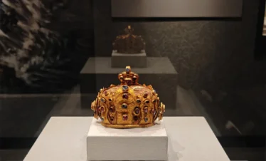 在 雲南國家寶藏館 展廳中，一頂鑲嵌紅藍寶石的金冠陳列於玻璃展櫃內，在燈光映照下展現出華麗質感與濃厚歷史氛圍。