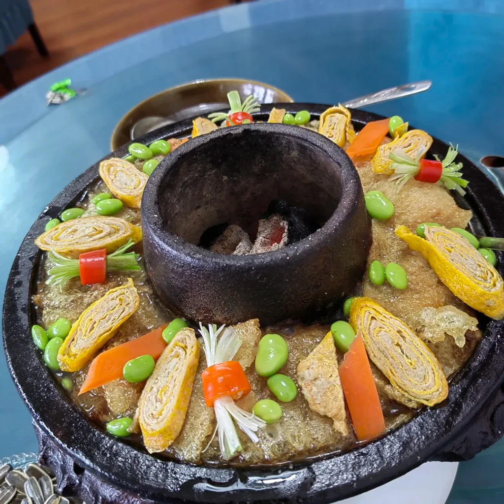 Tengchong earthen pot 地道騰衝土鍋子,雲南傳統火鍋特色料理。手工黑陶鍋內鋪滿蛋卷、毛豆、炸豬皮,以濃郁湯頭慢燉。