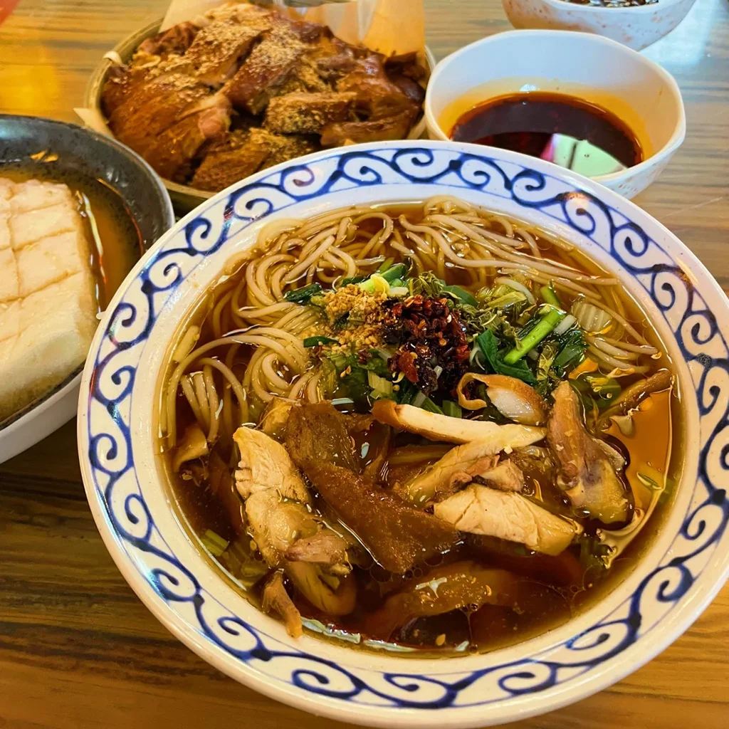 地道昆明鹵雞米線，雲南經典早餐。Q 彈米線盛於鹵香湯頭，鋪上嫩鹵雞肉、香草、辣椒油與花生。