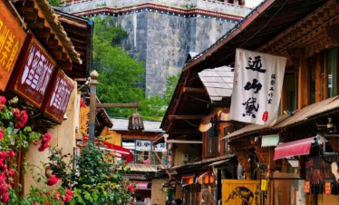 在 独克宗古城 街巷中，木质商铺林立，远处藏式建筑高耸，游客漫步其中，展现浓厚藏区风情。