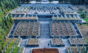 國殤墓園俯瞰景觀，整齊排列的士兵雕像與階梯式紀念廣場延伸至中央紀念碑，四周群山與松林環繞，象徵對滇西抗戰英烈的追思與敬意，是騰沖重要的歷史紀念與愛國教育場所。