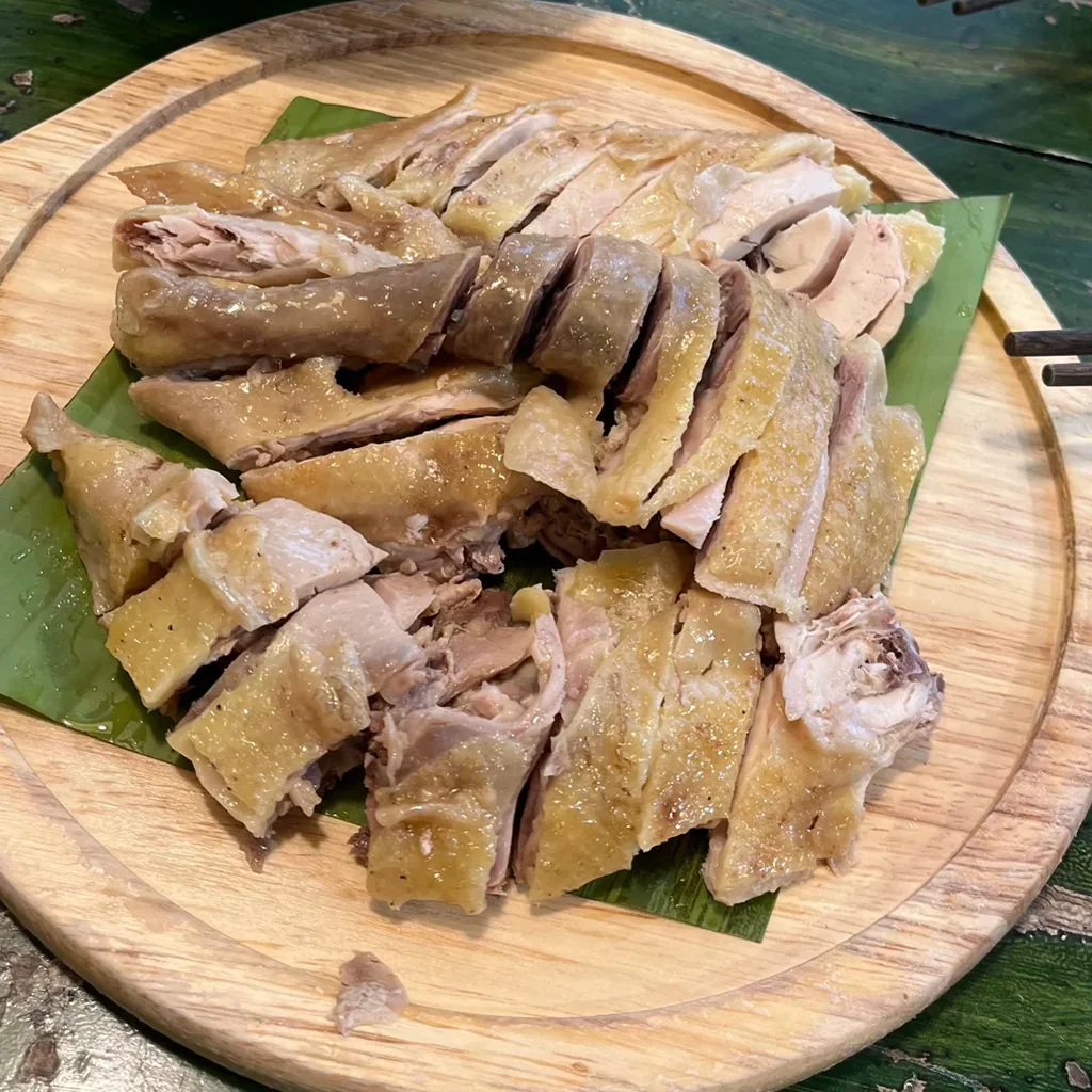 地道元陽哈尼蘸水雞，雲南特色料理。嫩白切雞切片盛於木盤，鋪上芭蕉葉，搭配香辣蘸水。