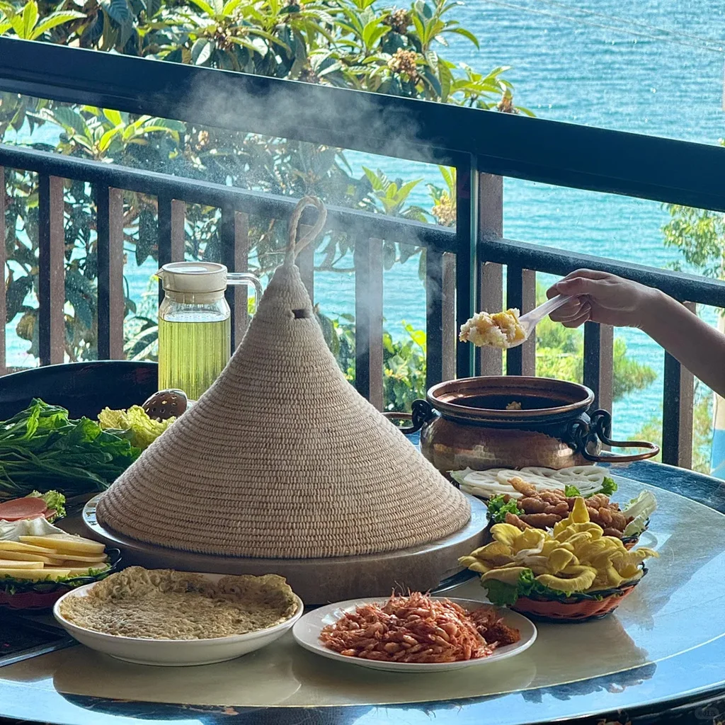 道地瀘沽湖石鍋魚，雲南湖畔特色料理。新鮮魚類以手工雕刻石鍋蒸製，覆蓋編織草蓋，搭配新鮮配菜與絕美湖景。