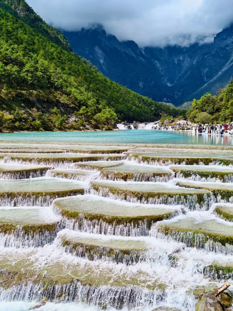 麗江藍月谷層層瀑布與藍色湖水，周圍環繞綠色山林。