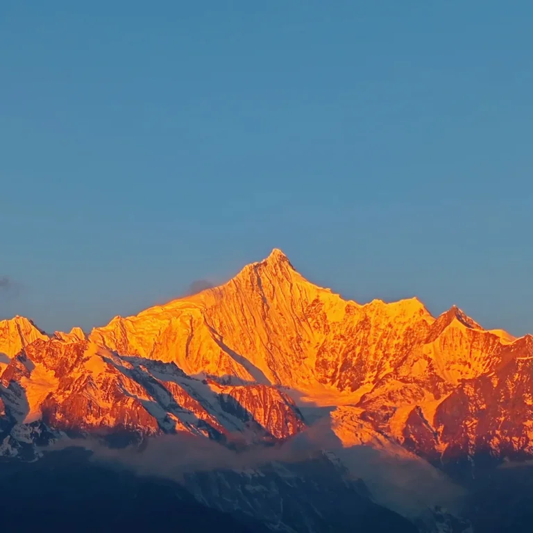香格里拉梅里雪山日照金山絕景，朝陽金光浸染萬年雪域主峰，無人登頂藏地神山聖境，澄藍晴空下金頂輝煌燦爛、氣勢萬千。