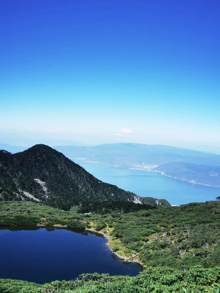 從蒼山俯瞰洱海，山峰與高山湖泊交織，遠方湖水蔚藍壯麗。