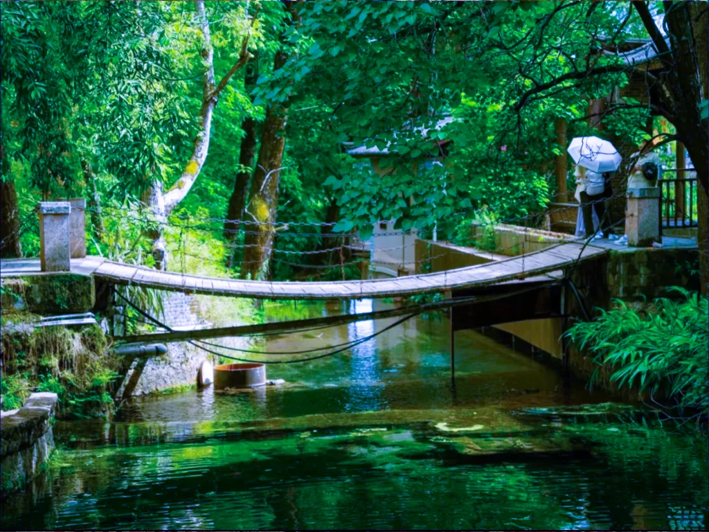 麗江束河古鎮內的寧靜吊橋，木橋橫跨澄澈溪流，四周是翠綠森林與傳統納西建築，盡顯古鎮清幽。