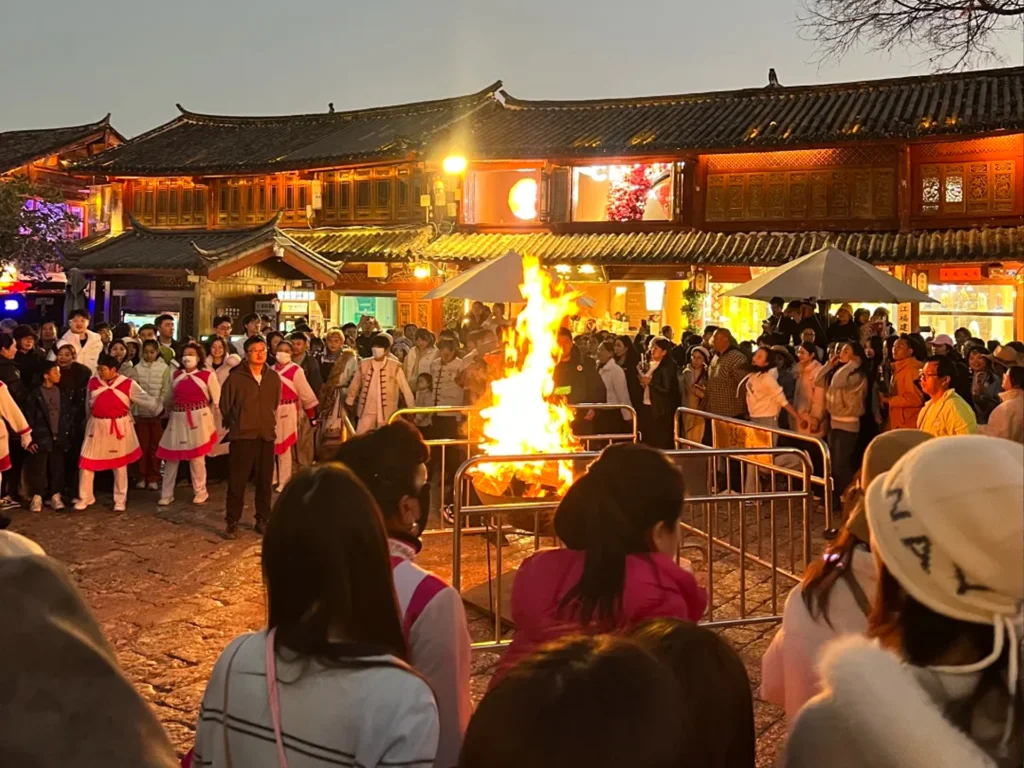 Sifang Street Lijiang Ancient Town 雲南麗江古城四方街篝火晚會,群眾圍繞熊熊篝火,背景是傳統納西建築與暮色天空。