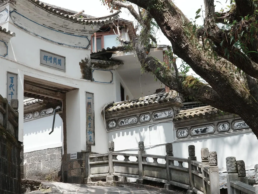 騰衝和順古鎮的白族傳統民居，白牆藍邊、飛檐翹角，古榕樹的枝椏斜倚在屋頂，是滇西僑鄉建築風情的典型模樣。