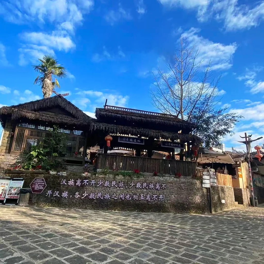 騰衝司莫拉佤族村的傳統茅草屋，青石板路、紅燈籠與藍天相映，是保存完好的佤族原生態古村落。