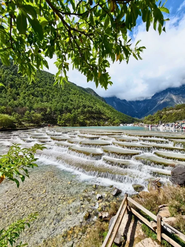 麗江藍月谷湖水清澈，森林與山脈在雲霧環繞下形成壯麗景觀。