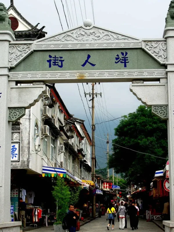 Dali Foreigners Street 1 e1774959761821 rlbgne1pufk5y5ujmitas5ics4m1b8s1o8ohqkmm2o 大理洋人街牌坊,傳統石雕門樓與街道景象,展現古城熱鬧氛圍。