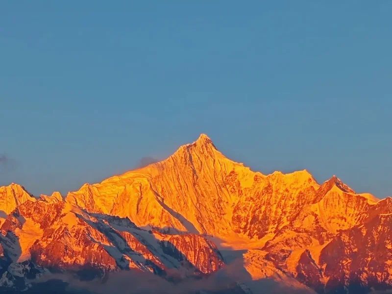 Meili Snow Mountain 清晨陽光照耀 梅里雪山,雪峰被金色光芒染亮,山體輪廓清晰壯麗,天空湛藍,呈現震撼的「日照金山」自然奇觀。