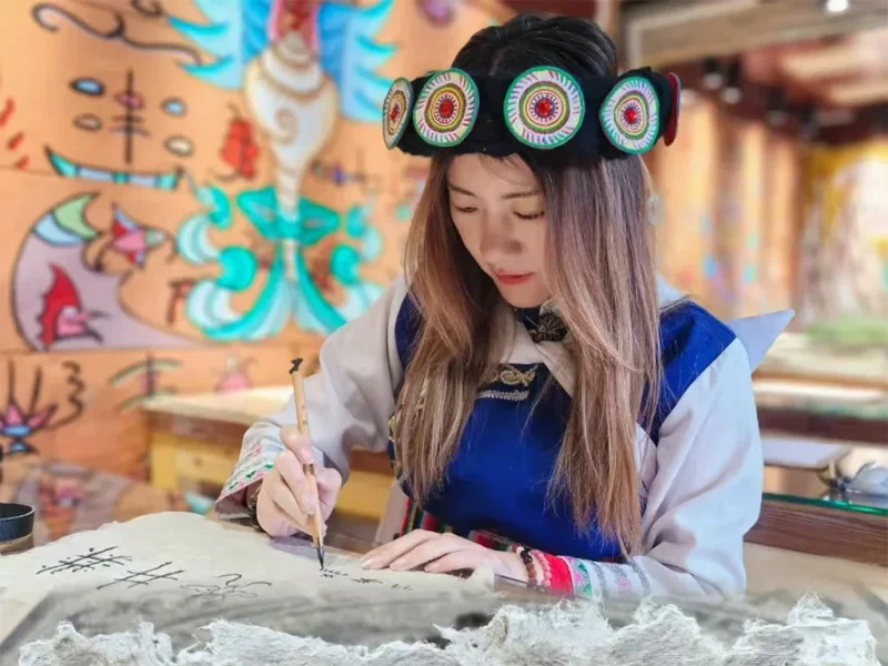 身穿納西服飾的遊客書寫東巴文字，體驗文化。