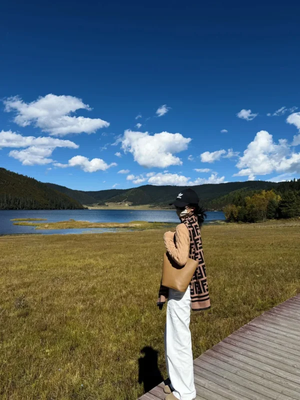 Shangri La Dacuo 3 秋日的普達措屬都湖,在木棧道上側身回眸,金黃草甸、湖泊與藍天白雲相映,是香格里拉最溫柔的高原秋日畫面。