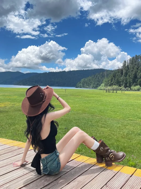 Shangri La Dacuo 在普達措屬都湖的草原上,戴著牛仔帽坐在木棧道上,綠草如茵、湖泊森林相映,是香格里拉最清新的森林草原畫面。