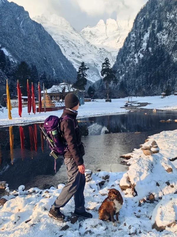 Shangri La Meili Snow Mountain 2 rnbwsle63sa0eoqb9dk3vj2yhwyktwagsgba6g8l6o 雨崩村冬日限定景觀,徒步者與狗狗站在結冰的湖畔,梅里雪山主峰倒映水中,宛如人間仙境。