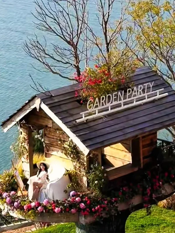 Slow Living in a Dali Erhai Log Cabin 大理洱海小木屋慢生活場景,湖畔木屋環繞花卉,一人悠閒享受寧靜時光。