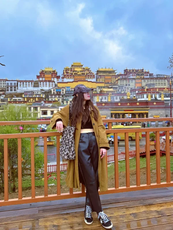 Songzanlin Monastery Shangri La 2 在松贊林寺前的木平台上,靠著欄杆遠望「小布達拉宮」,雨後的寺廟與焦糖色穿搭相映,是香格里拉最具故事感的打卡畫面。